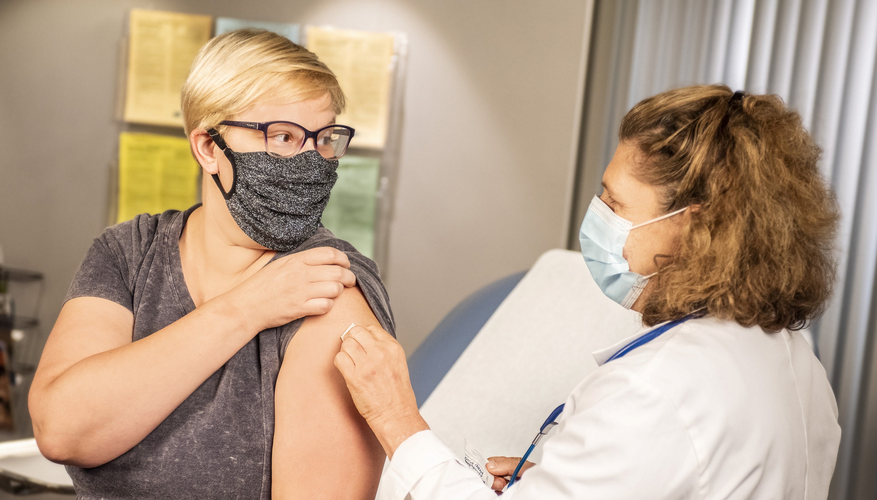 A health care provider placing a bandage on the injection site of a woman