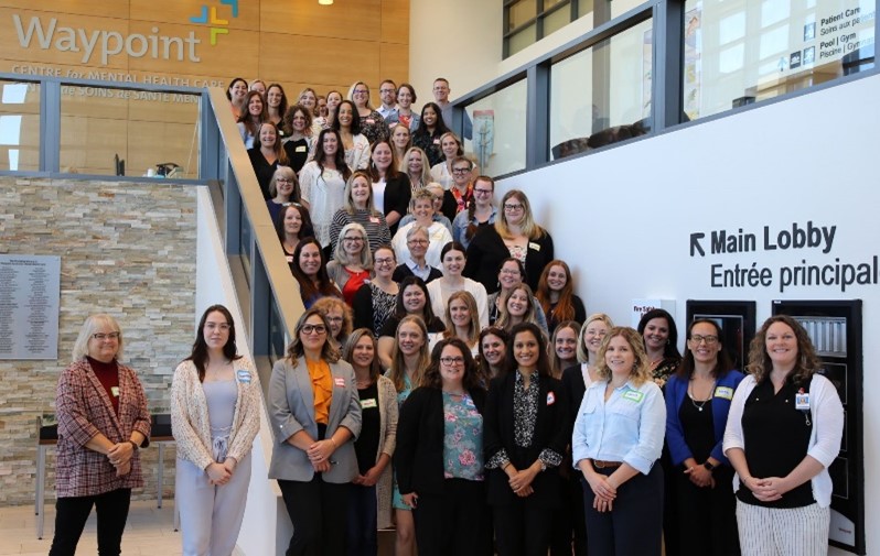 A group of smiling people standing together on the stairs of a conference centre