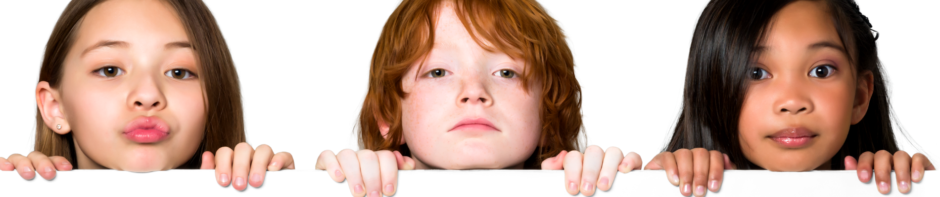 three children's faces peeking over a wall