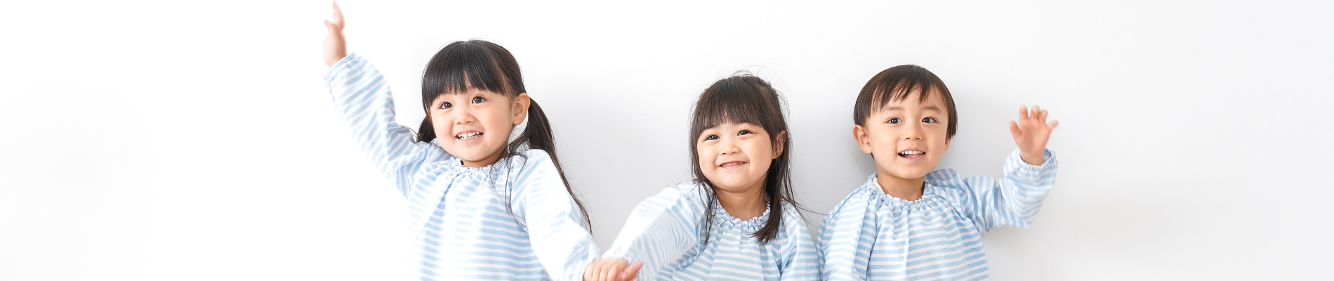 three Asian children in matching outfits smiling