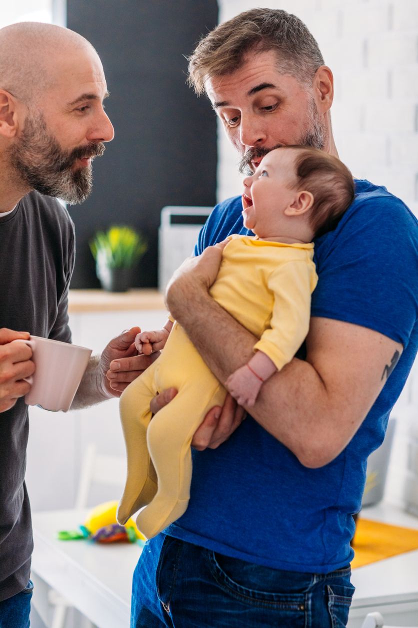 Deux papas avec un bébé souriant