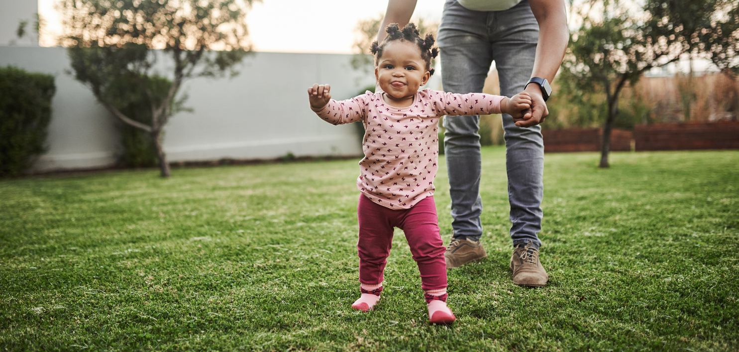 toddler learning to walk in the grass