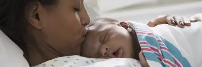 Mom in the hospital, kissing her newborn's head