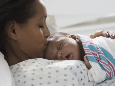 Mom in the hospital, kissing her newborn's head